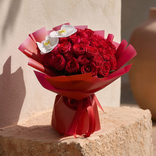 Hand-tied bouquet of 35 red roses with orchid stems in elegant red wrapping by Aiwa Flowers Dubai