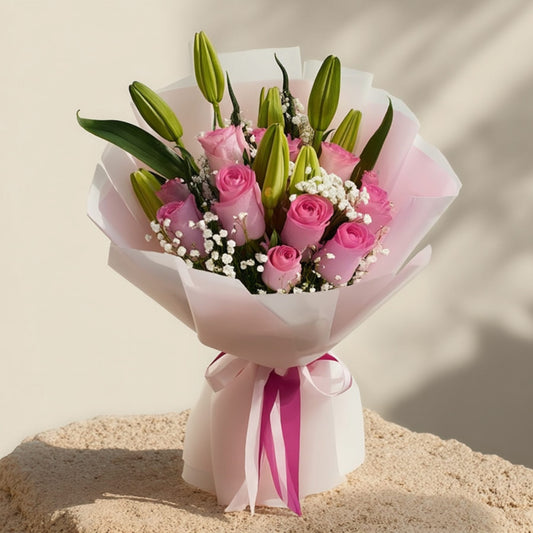 Hand-tied bouquet of pink roses, lilies, and gypsophila in elegant white wrapping, handcrafted by Aiwa Flowers in Dubai