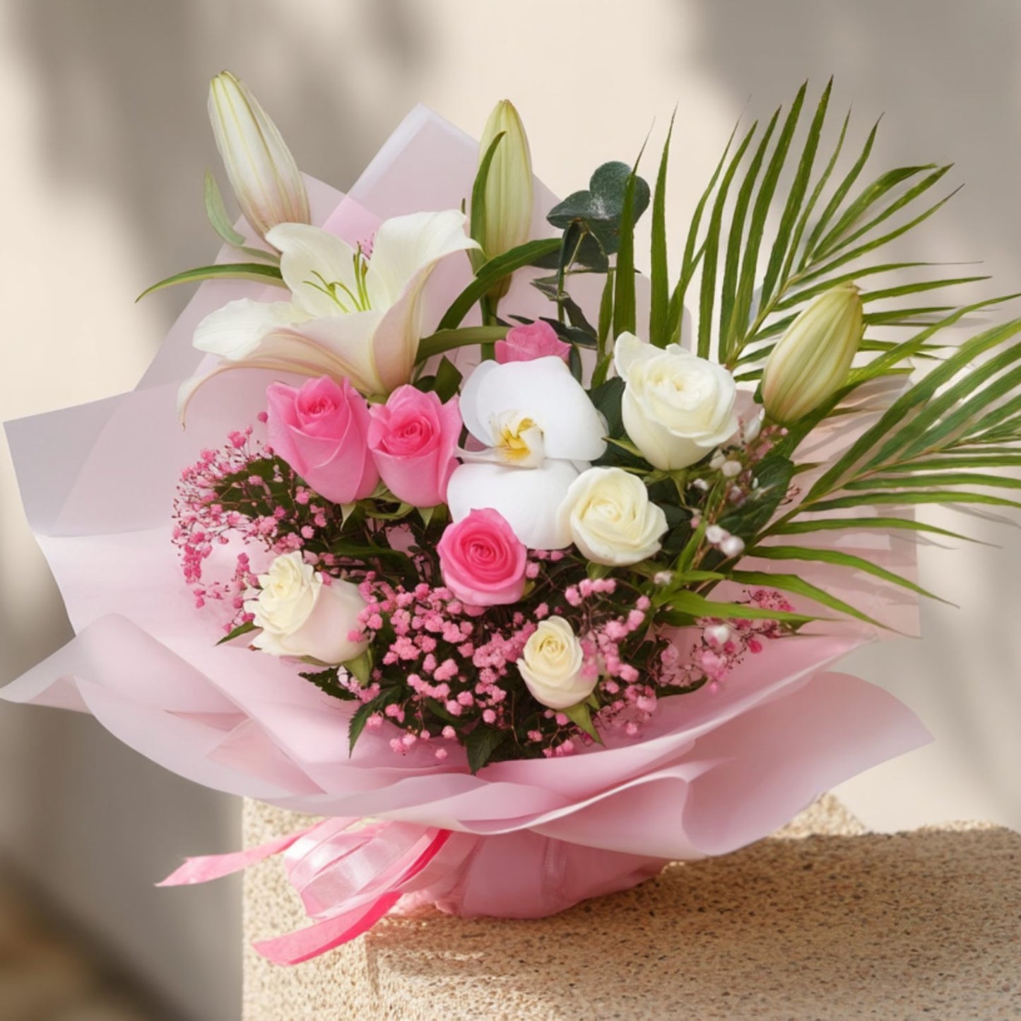 Handcrafted bouquet with pink and white roses, lily, white orchid, pink gypsophila, and greenery in soft pink wrapping by Aiwa Flowers Dubai