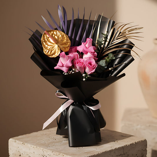 Hand-tied bouquet of pink roses with gypsophila, eucalyptus, and anthurium wrapped in elegant black paper
