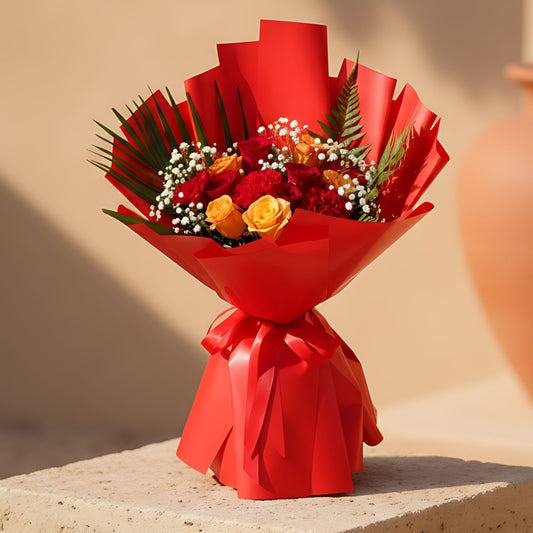 Hand-tied bouquet of red and orange roses with carnations, gypsophila, and greenery wrapped in red paper