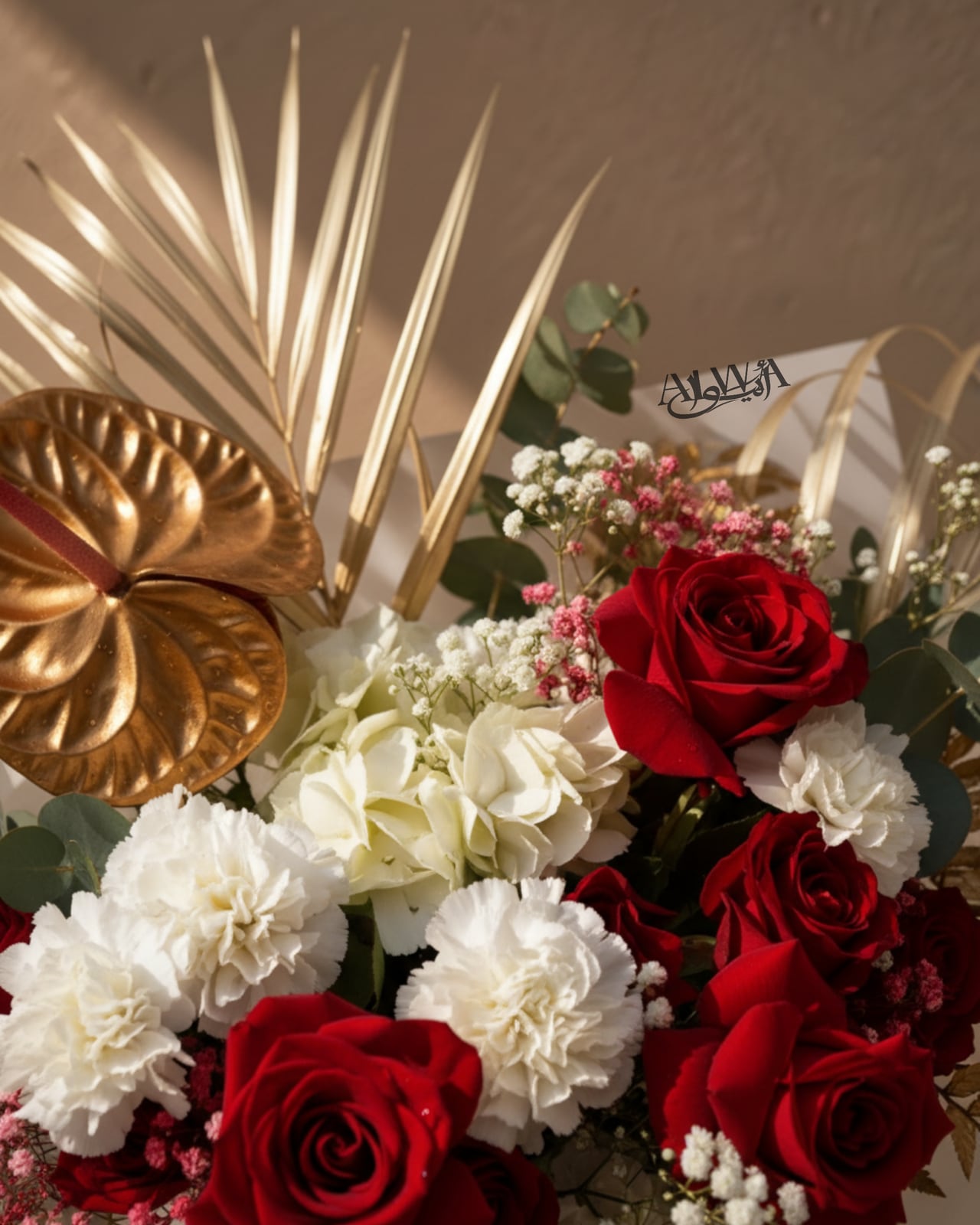 Close-up of red roses, white carnations and gold accents by AIWA Flowers Dubai