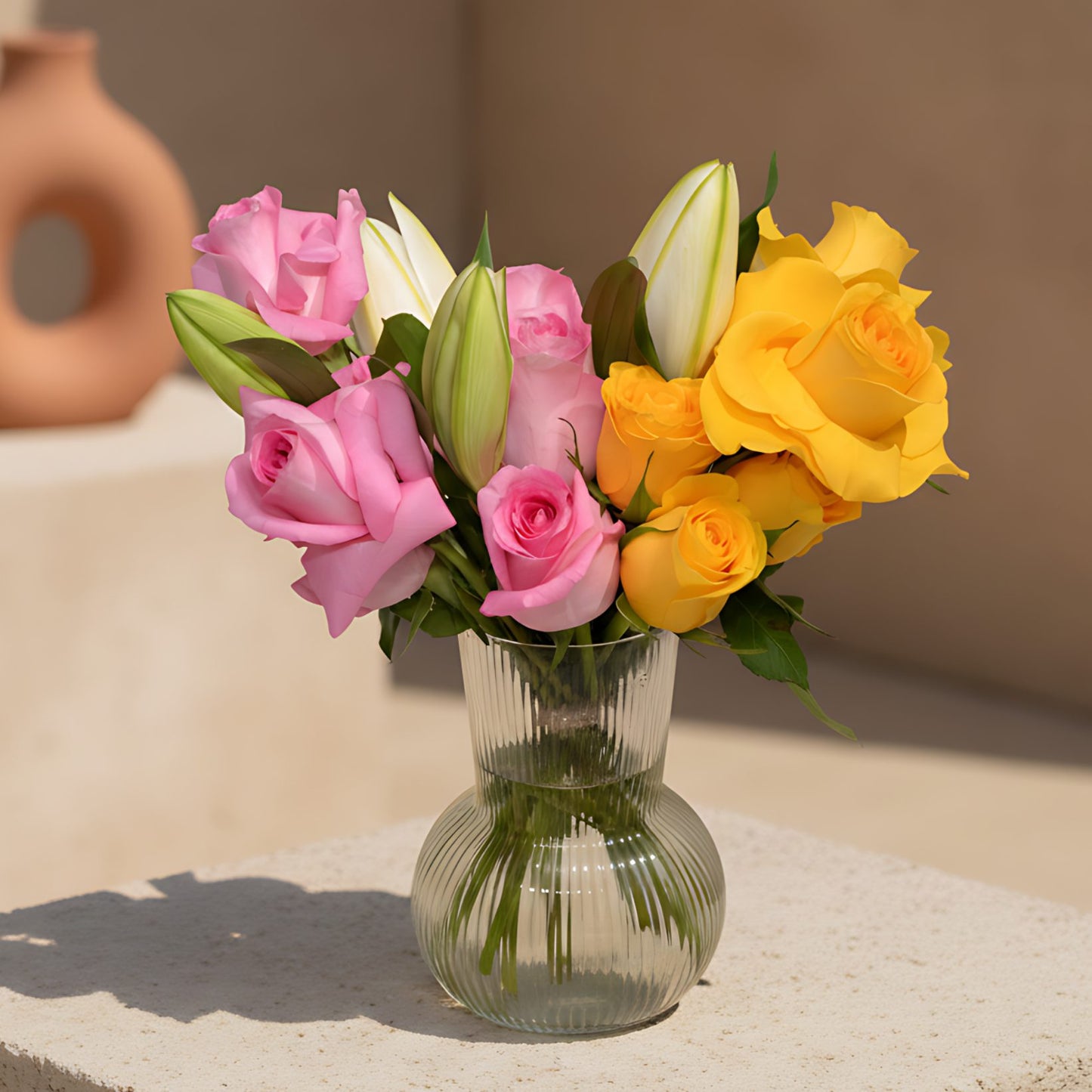 Lucy arrangement with pink and yellow roses and lilies in a clear glass vase
