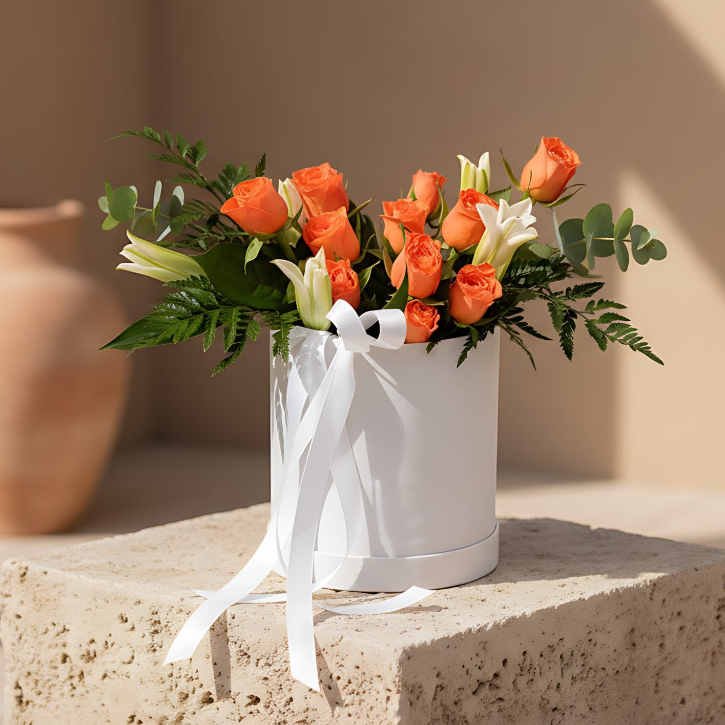 Tangelo white velvet round flower box with orange roses, white lilies, eucalyptus and fern