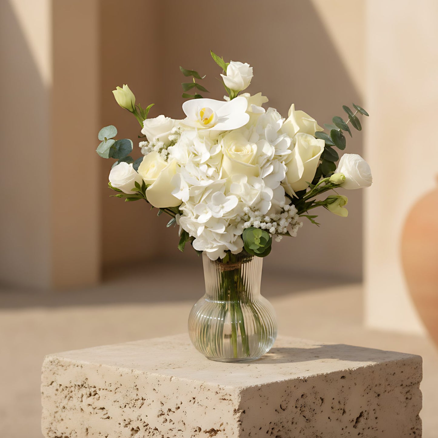 Vanessa arrangement with white roses, white hydrangea, orchid and eucalyptus in a clear glass vase