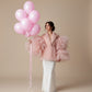 Woman holding bouquet of 10 pink helium balloons