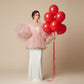 Woman holding bouquet of 10 red helium balloons tied with long ribbons