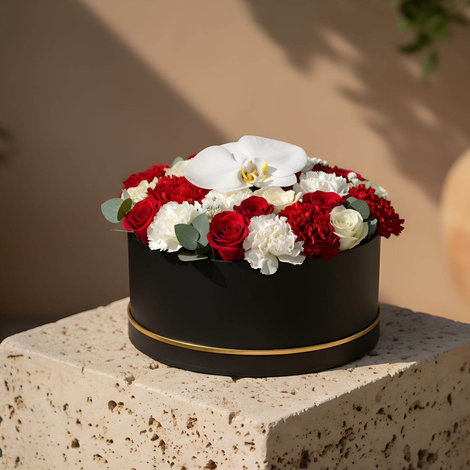 Black box floral arrangement with red and white roses, carnations, white orchid, eucalyptus, and gypsophila