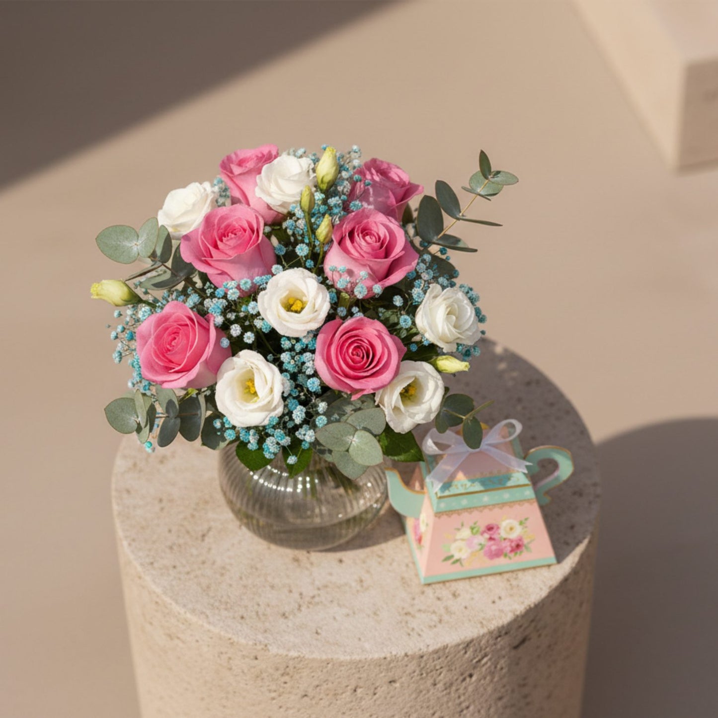 Top view of Bloom for Her Vase bouquet with pink roses and white lisianthus beside decorative floral tea-pot gift box.