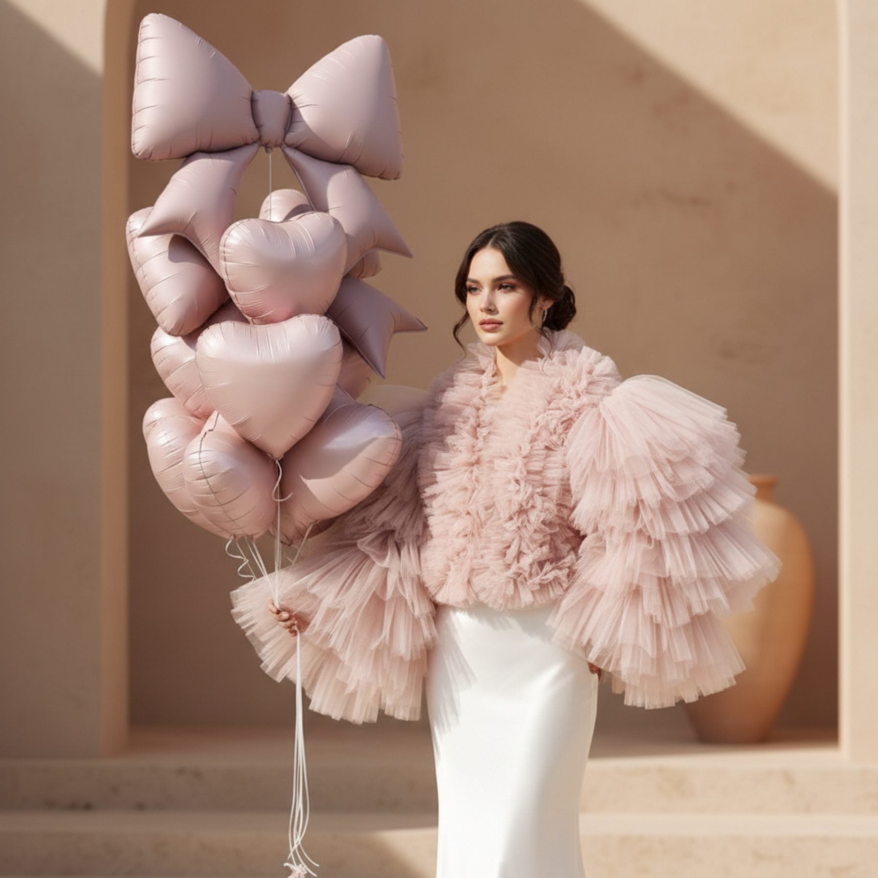 Woman holding Blush Bow Bundle balloon bouquet with blush heart balloons and oversized bow balloon.
