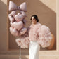 Woman holding Blush Bow Bundle balloon bouquet with blush heart balloons and oversized bow balloon.