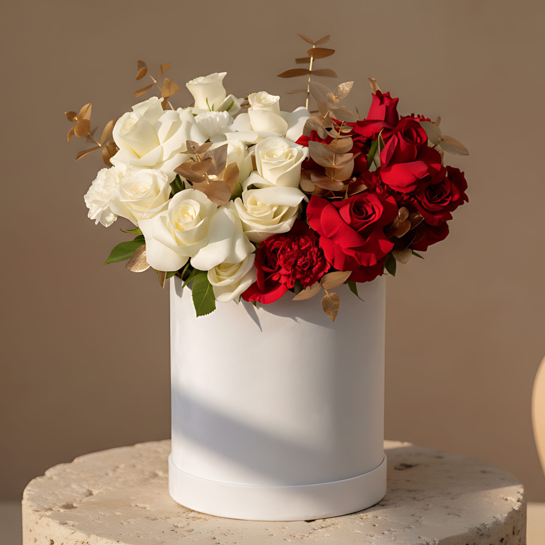 White velvet box arrangement with red and white roses, red and white carnations, and gold eucalyptus