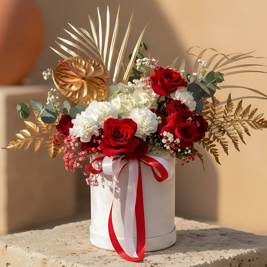 White velvet box arrangement with red roses, white hydrangea, carnations, gypsophila, and gold accents