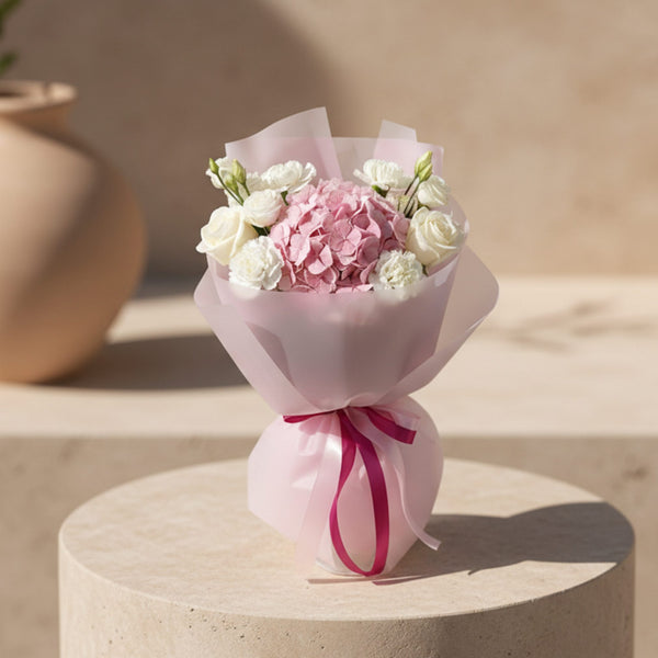 Deva bouquet with pink hydrangea, white roses, and white flowers wrapped in soft pink paper.