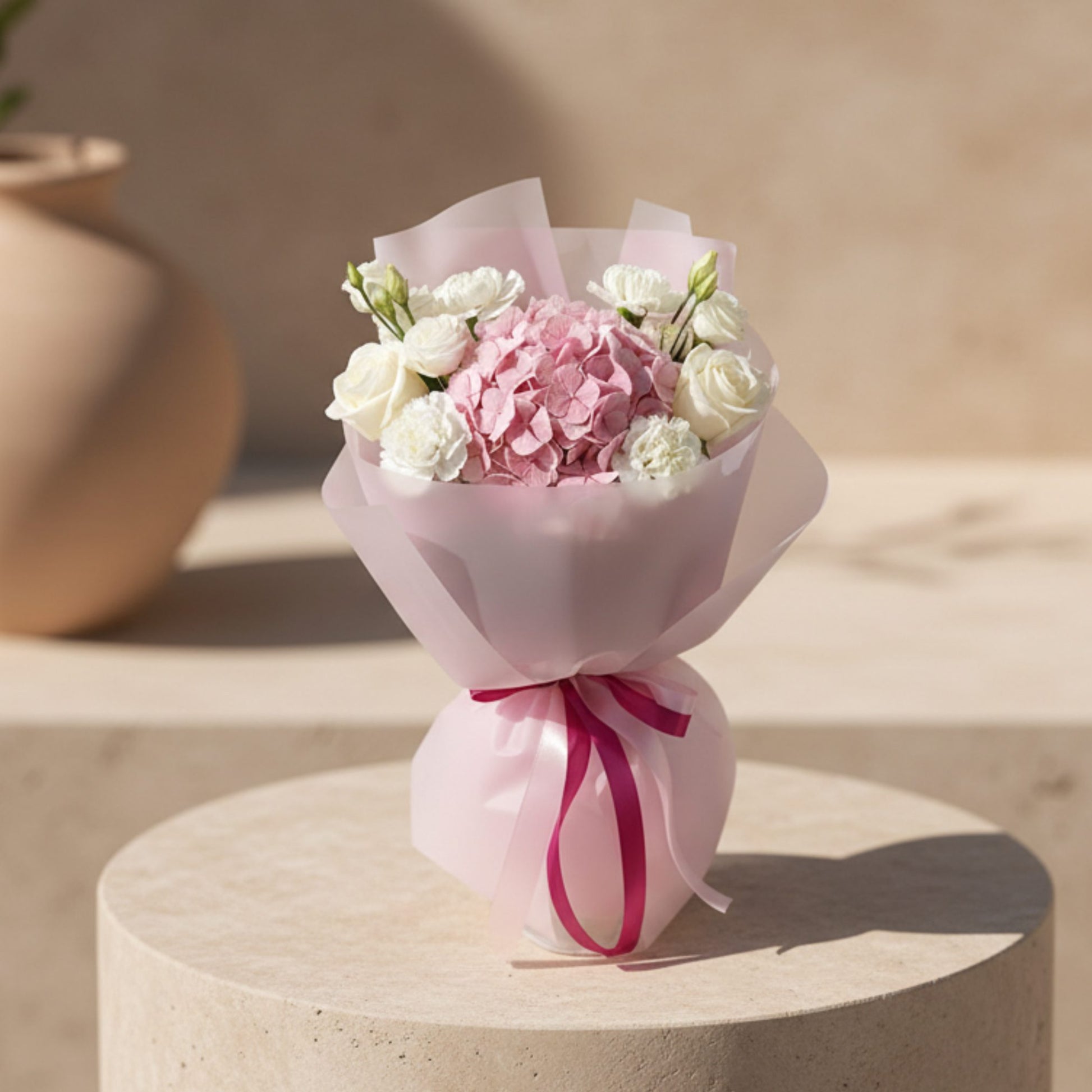 Deva bouquet with pink hydrangea, white roses, and white flowers wrapped in soft pink paper.