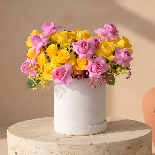 White velvet box arrangement with pink and yellow roses and matching gypsophila