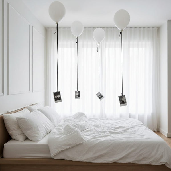 white helium balloons with attached photos floating above bed minimal room decoration Dubai
