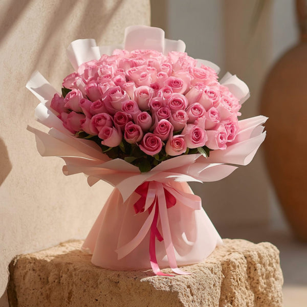 Hand-tied bouquet of 101 pink roses in soft light pink wrapping by Aiwa Flowers Dubai
