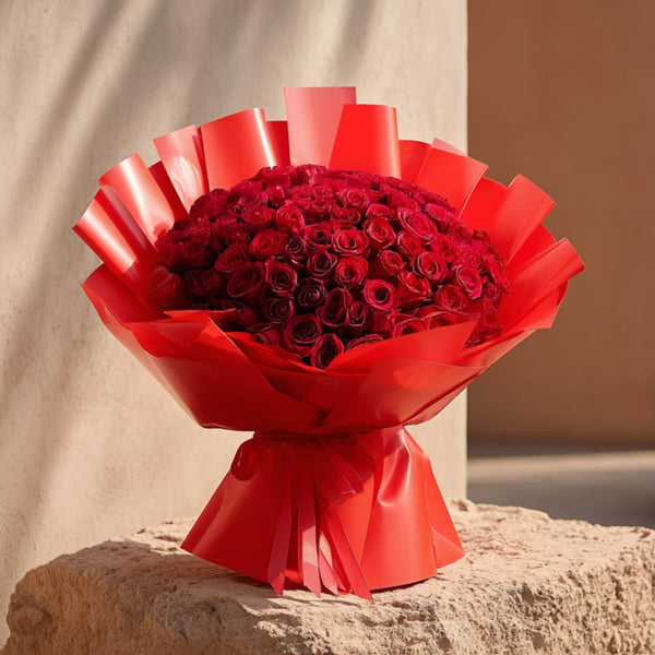 Hand-tied bouquet of 101 red roses in elegant red wrapping by Aiwa Flowers Dubai
