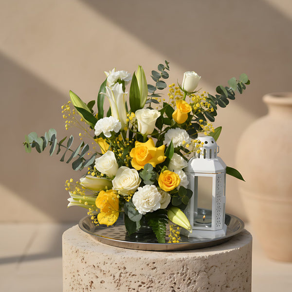Ahlan floral tray arrangement with white and yellow roses, carnations, lilies, eucalyptus, yellow gypsophila, and white lantern by Aiwa Flowers Dubai