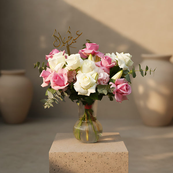 Al Adha Fest floral arrangement with pink and white roses, lilies, hydrangeas, eucalyptus, and Arabic topper in clear vase by Aiwa Flowers Dubai