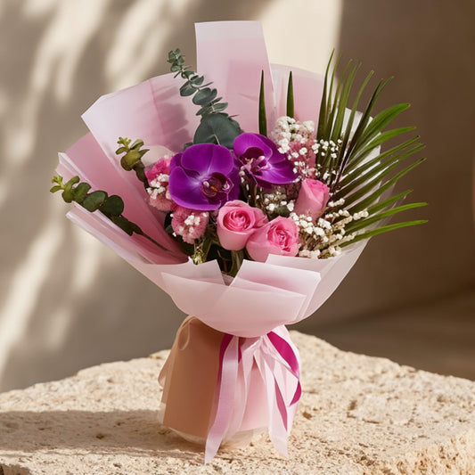 Hand-tied bouquet with purple orchids, pink roses, gypsophila, and eucalyptus in soft light pink wrapping by Aiwa Flowers Dubai
