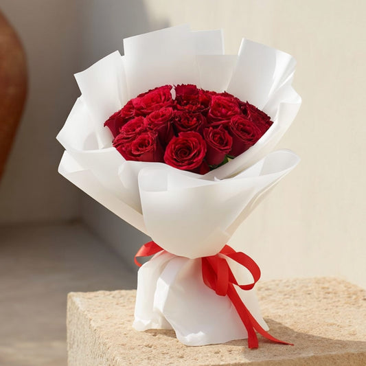 Hand-tied bouquet of 15 red roses in elegant white wrapping by Aiwa Flowers Dubai