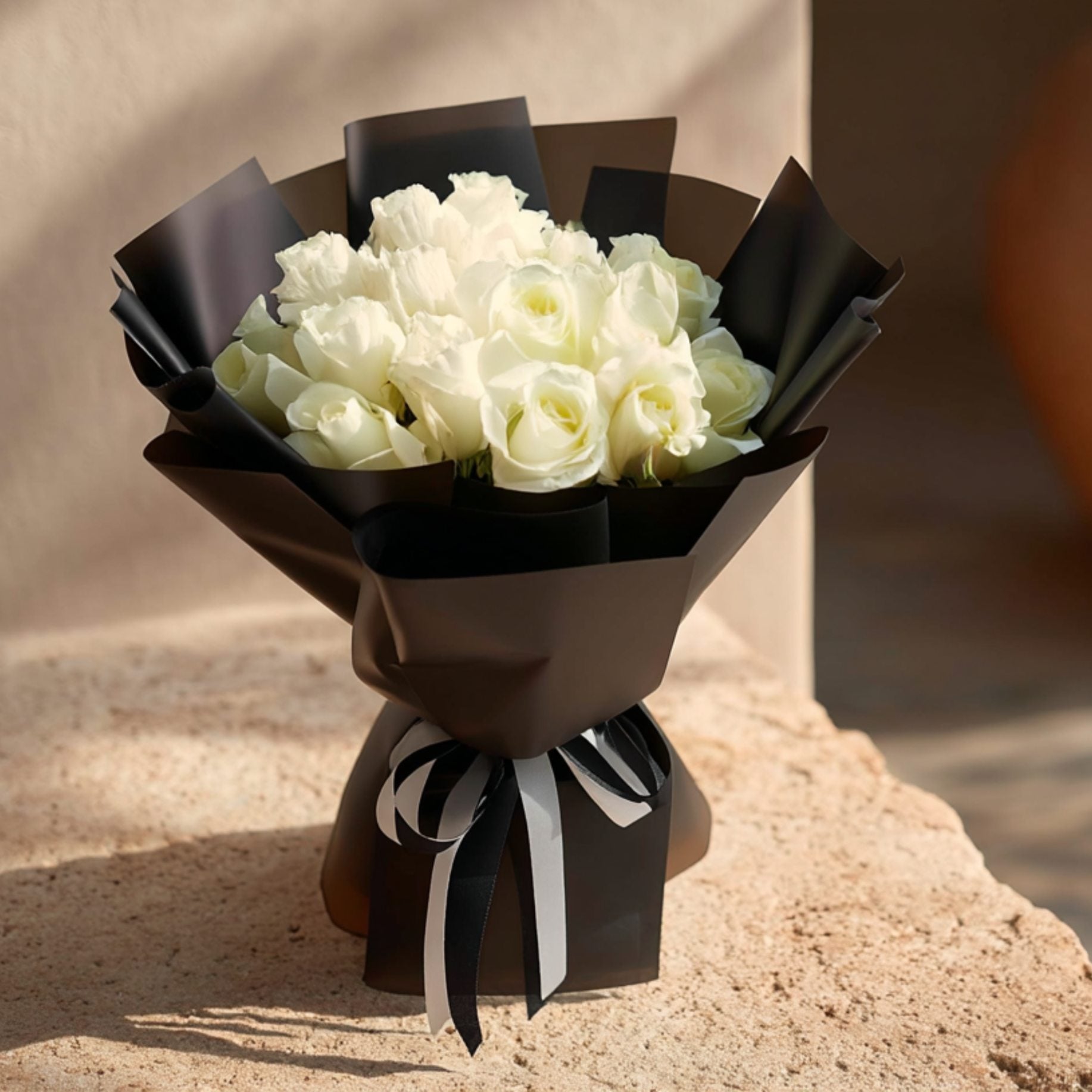 Hand-tied bouquet of 15 white roses in elegant black wrapping by Aiwa Flowers Dubai
