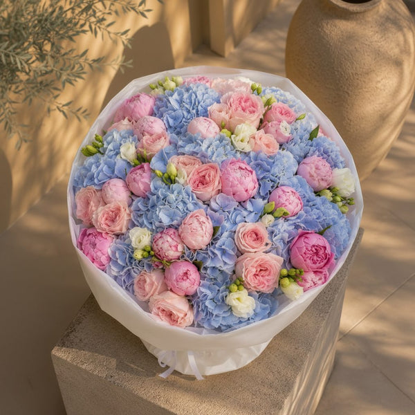 Luxury bouquet featuring blue hydrangeas, pink peonies and blush roses in white wrapping, handcrafted in Dubai.
