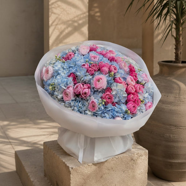 Romantic bouquet of blue hydrangeas and pink roses in white wrapping, luxury flower delivery by Aiwa Flowers Dubai.