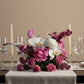 Blush pink rose and white orchid floral centerpiece arranged on an elegant dining table.