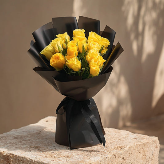 Hand-tied bouquet of 15 yellow roses in elegant black wrapping by Aiwa Flowers Dubai
