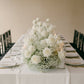 1 meter ivory rose and gypsophila elongated table centerpiece arranged on a formal dining table.