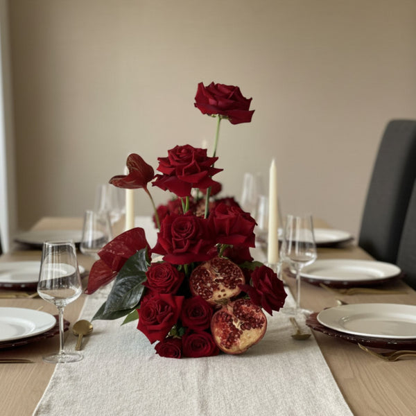 Luxury red rose and pomegranate floral centerpiece arranged for an elegant dining table setting.