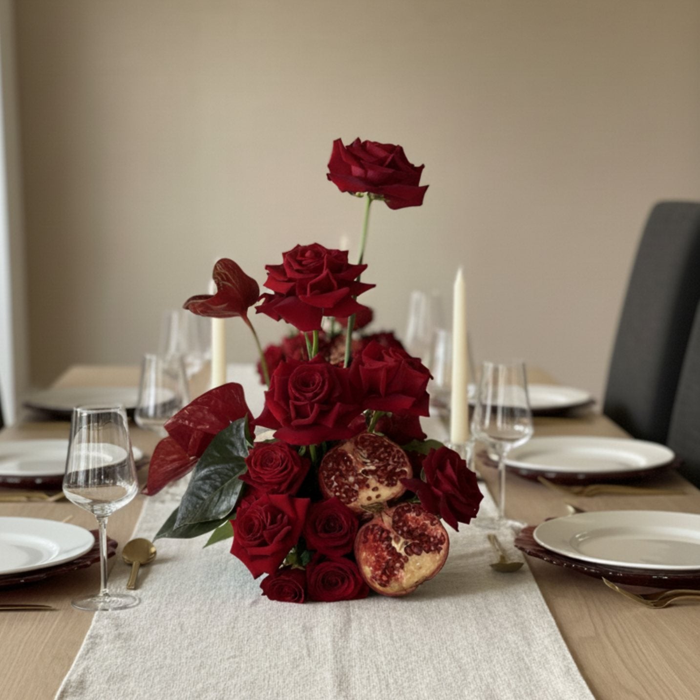 Luxury red rose and pomegranate floral centerpiece arranged for an elegant dining table setting.