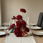 Luxury red rose and pomegranate floral centerpiece arranged for an elegant dining table setting.
