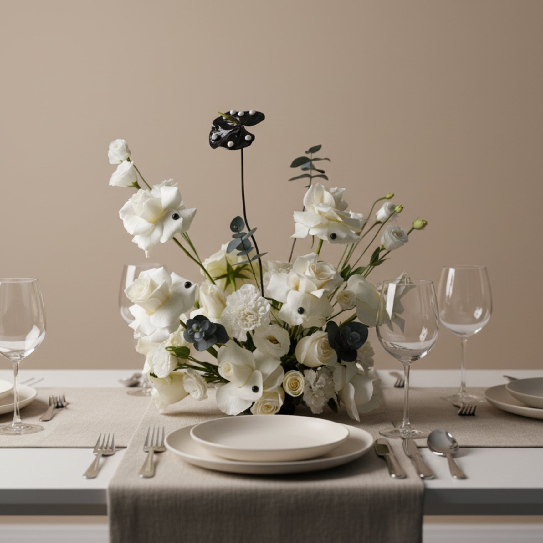 Domino centerpiece with ivory roses and modern black accents arranged on an elegant dining table.