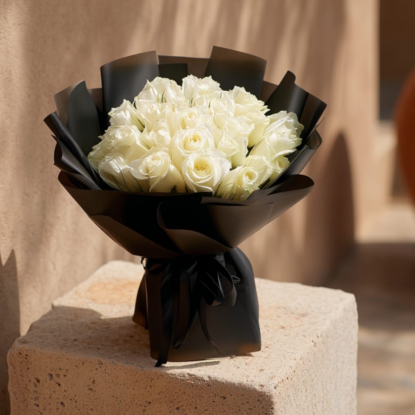 Hand-tied bouquet of 25 white roses in elegant black wrapping, handcrafted by Aiwa Flowers in Dubai
