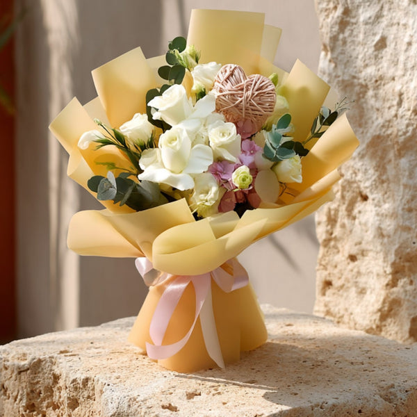 Hand-tied bouquet of white roses with lisianthus, pink hydrangea, eucalyptus, and a heart detail in gold wrapping by Aiwa Flowers Dubai

