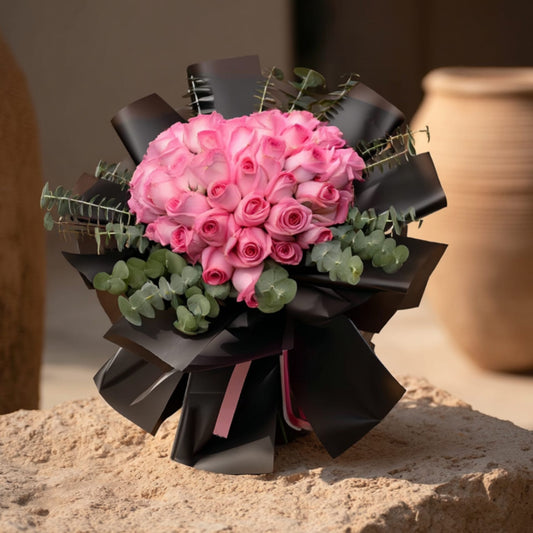 Heart-shaped hand-tied bouquet of pink roses in elegant black wrapping by Aiwa Flowers Dubai
