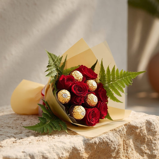 Bouquet of 10 red roses with 5 Ferrero Rocher chocolates and fern leaves in elegant gold wrapping by Aiwa Flowers Dubai
