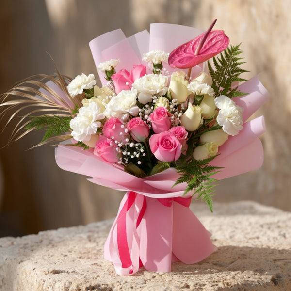 Hand-tied bouquet of pink and white roses with carnations, gypsophila and pink anthurium in soft pink wrapping by Aiwa Flowers Dubai
