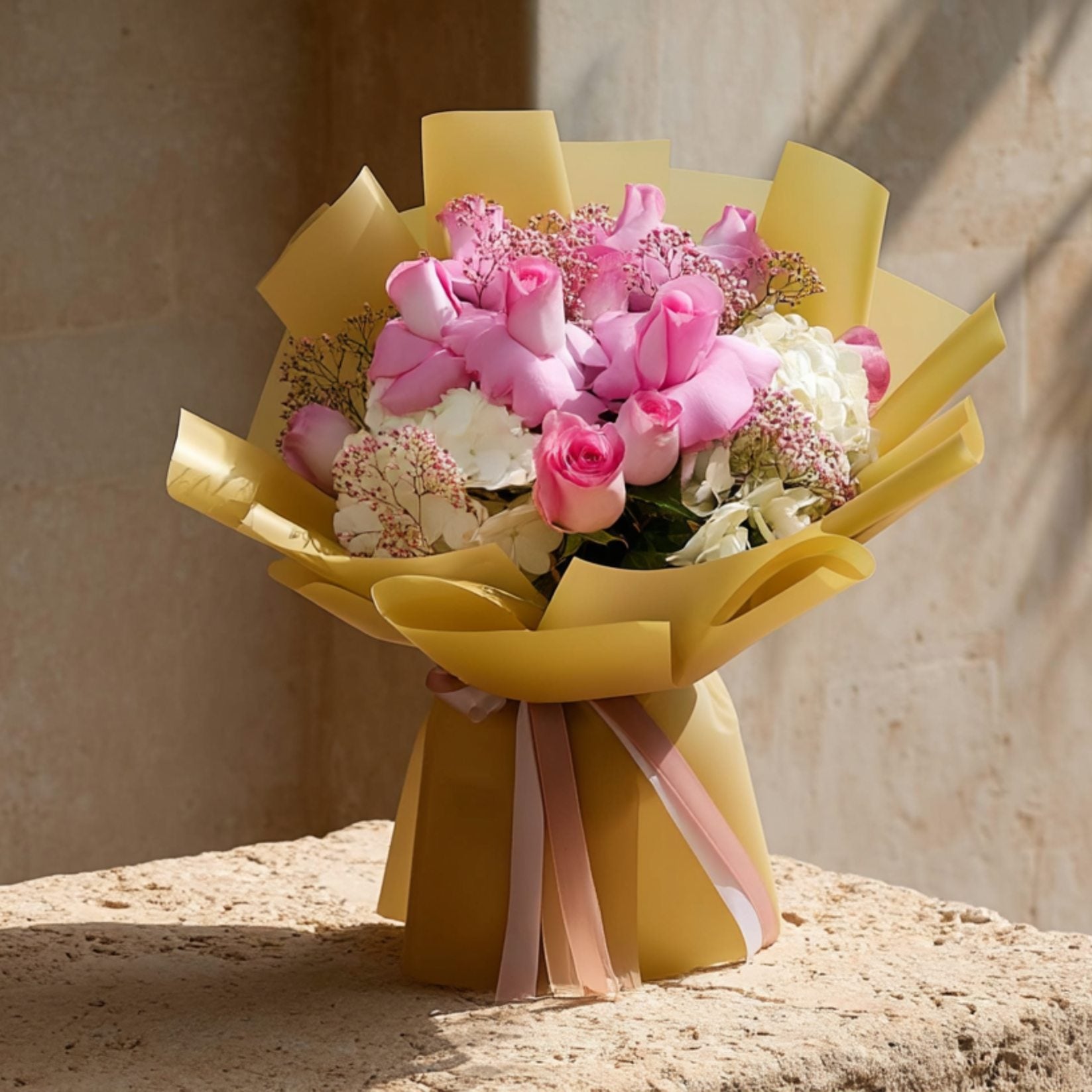 Hand-tied bouquet of pink roses with white hydrangeas and gypsophila in elegant gold wrapping by Aiwa Flowers Dubai
