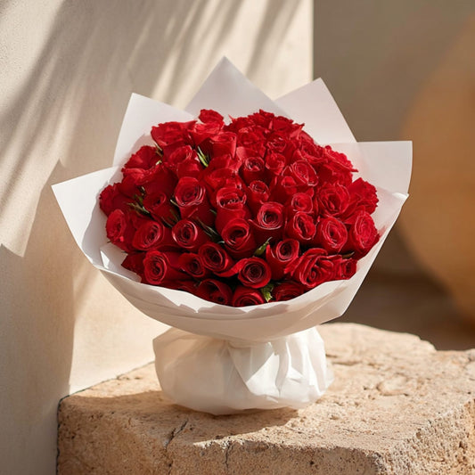 Hand-tied bouquet of 55 red roses in elegant white wrapping by Aiwa Flowers Dubai

