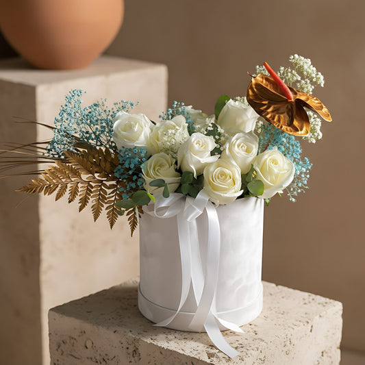 Freeze white velvet box arrangement with white roses, blue gypsophila, golden anthurium, and foliage by Aiwa Flowers Dubai