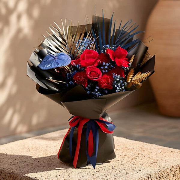 Hand-tied bouquet with red roses, carnations, and a blue anthurium in elegant black wrapping by Aiwa Flowers Dubai

