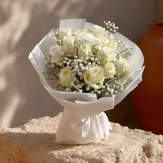 Hand-tied bouquet of white roses and gypsophila in elegant white wrapping by Aiwa Flowers Dubai
