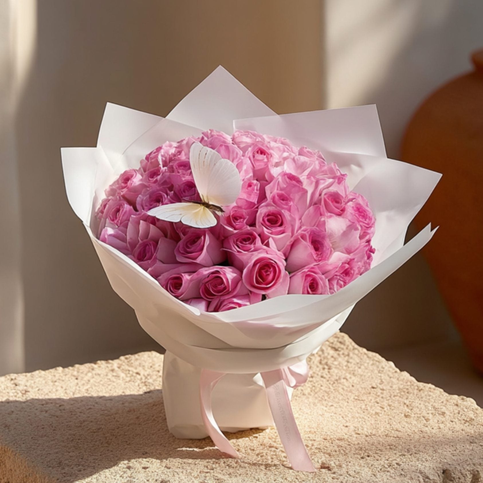 Hand-tied bouquet of 55 pink roses with a butterfly accent in elegant white wrapping by Aiwa Flowers Dubai
