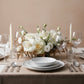 Elegant ivory rose and white lisianthus floral centerpiece arranged on a dining table with soft neutral styling.