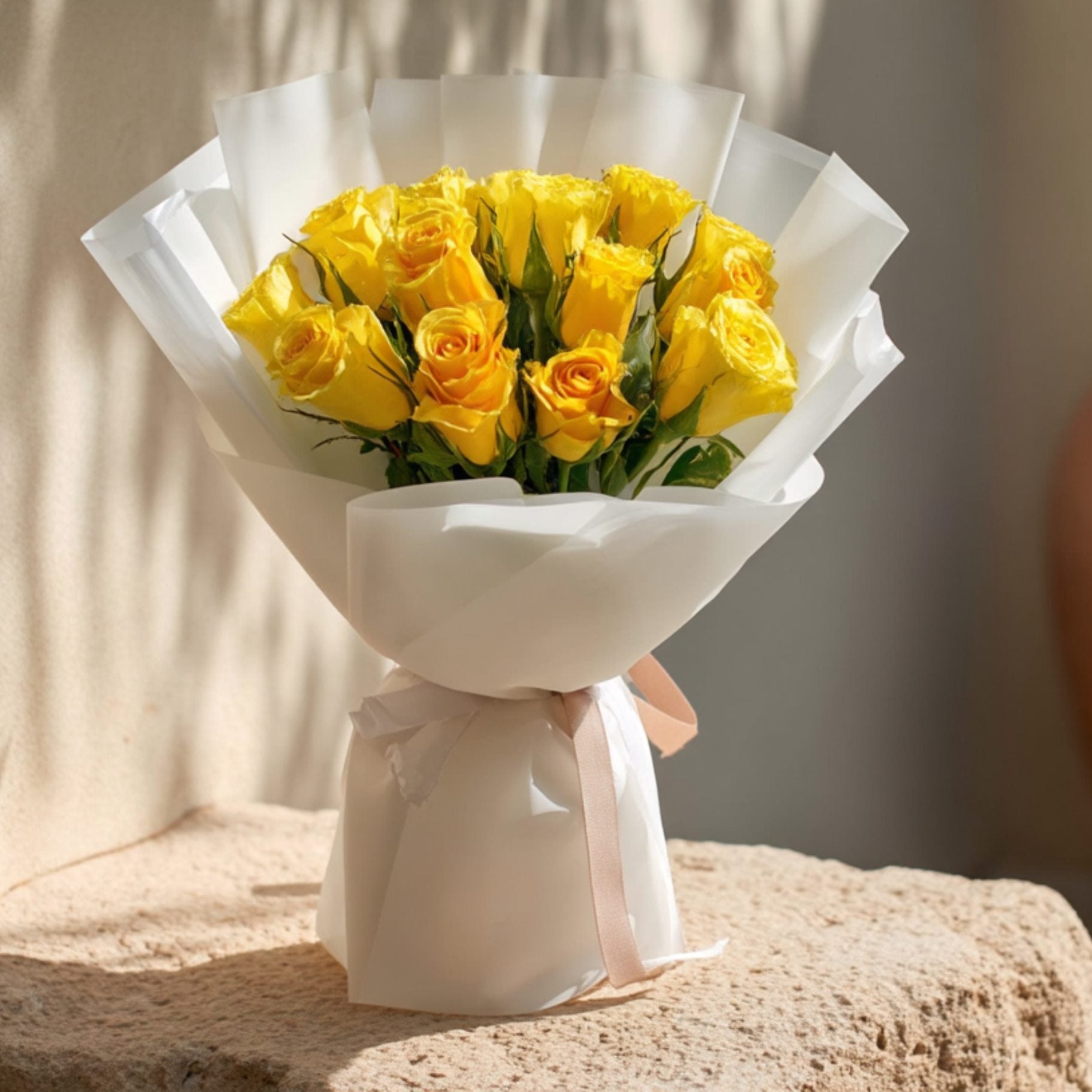 Hand-tied bouquet of 15 yellow roses in elegant white wrapping by Aiwa Flowers Dubai
